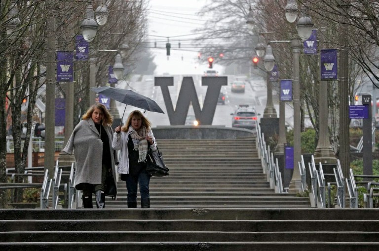 Two pedestrians share an umbrella in the rain, Friday, Dec. 29, 2017, in downtown Tacoma, Washington.