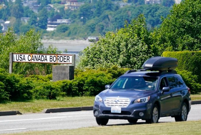 A car heads into the U.S. from Canada at the Peace Arch border crossing Tuesday, June 8, 2021, in Blaine, Wash. The border has been closed to nonessential travel since March 2020. (AP Photo/Elaine Thompson)