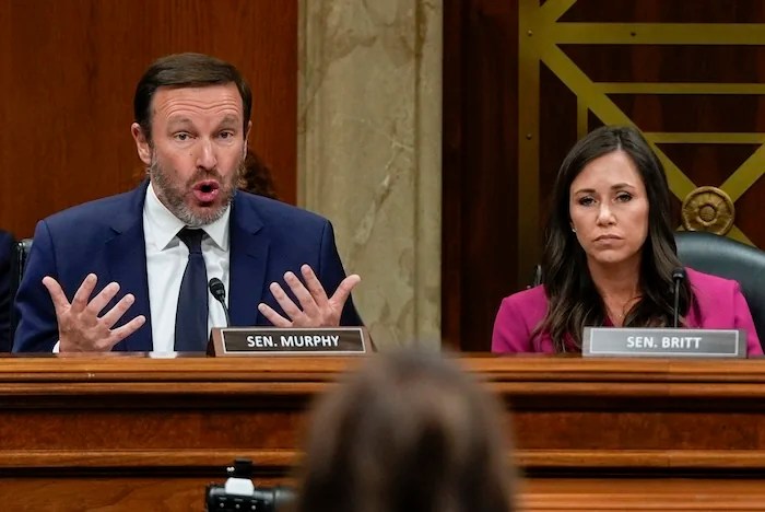 Sen. Chris Murphy, D-Conn., left, questions Homeland Security Secretary Kristi Noem, in foreground at center, as Sen. Katie Britt, R-Ala., right, looks on, during a Senate Appropriations Subcommittee on Homeland Security oversight hearing, Thursday, May 8, 2025, on Capitol Hill in Washington. (AP Photo/Julia Demaree Nikhinson)
