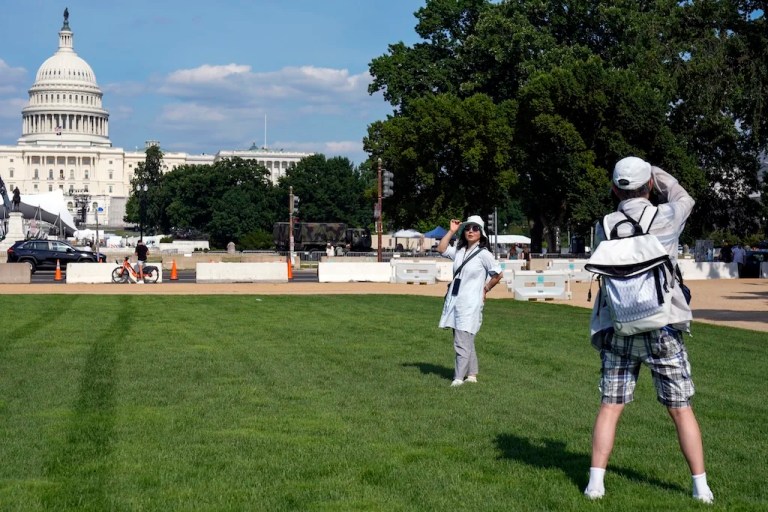 A visitor poses for a photo on the National Mall near the U.S. Capitol, Wednesday, July 3, 2024, in Washington, ahead of the Fourth of July celebrations. (AP Photo/Mariam Zuhaib)