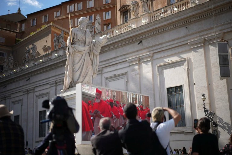 Photographers take pictures of a giant screen showing images of cardinals entering the conclave, in St. Peter's Square at the Vatican, Wednesday, May 7, 2025.