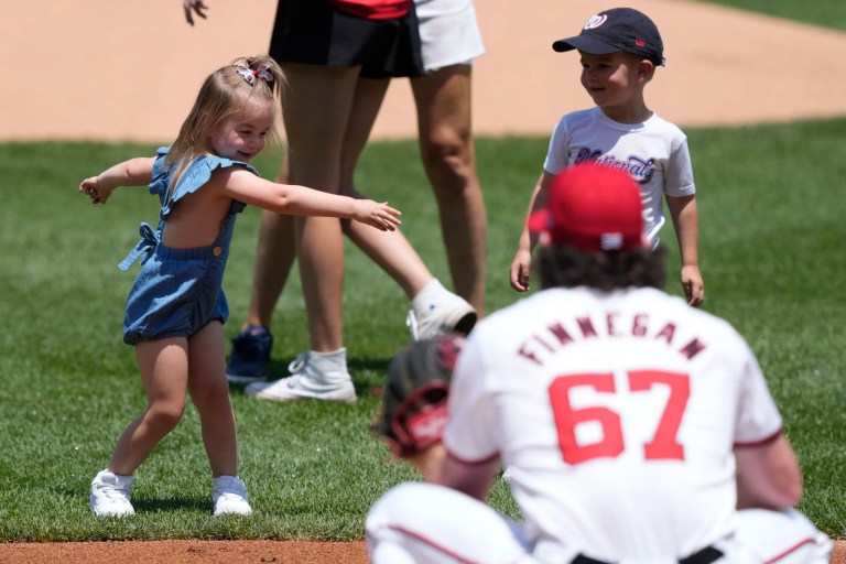 Washington Nationals relief pitcher Kyle Finnegan (67) waits for his daughter Carson, left, as his son Cooper, right, watches Carson dance after the children threw out ceremonial first pitches for Father's Day before a baseball game against the Miami Marlins at Nationals Park in Washington, Sunday, June 16, 2024.