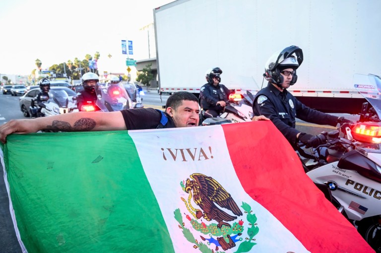 Roberto Alvarez waves a Mexican flag as police officers move protesters out of a street Friday, June 13, 2025, in Los Angeles.