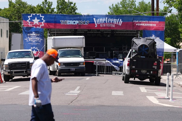 Volunteer passes by the stage for musical acts to perform at the Juneteenth celebration in the Five Points neighborhood where the event is staged Saturday, June 14, 2025, in Denver.