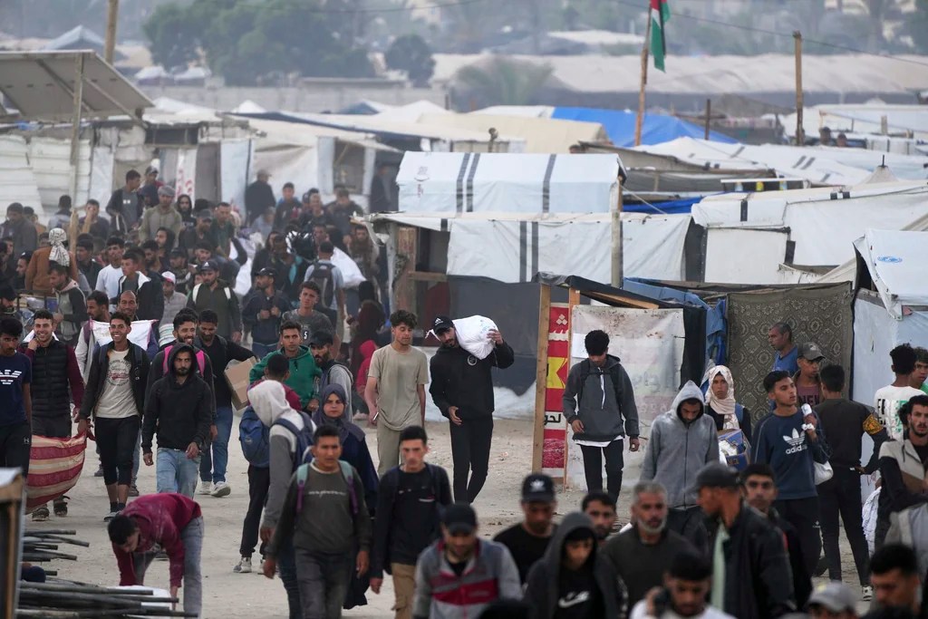 Palestinians carry bags filled with food and humanitarian aid provided by the Gaza Humanitarian Foundation, a U.S.-backed organization approved by Israel, in Khan Younis, southern Gaza Strip, on Tuesday, June 3, 2025.