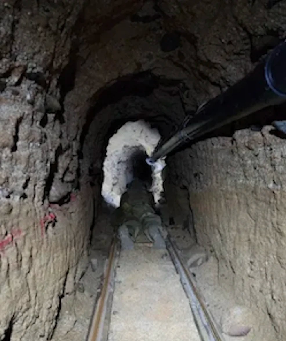 Inside the smuggling tunnel, a Tunnel Team agent crawls along the track. (U.S. Customs and Border Protection)