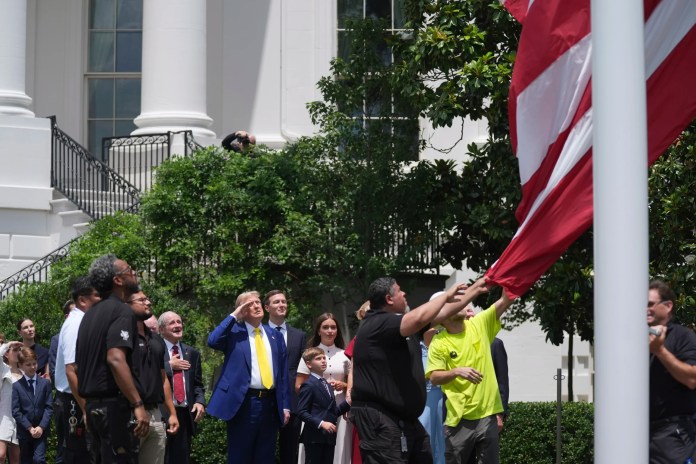President Donald Trump salutes as a flag is raised on a newly installed flag.
