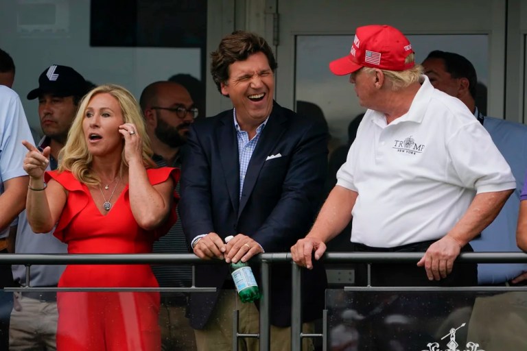 U.S. Rep. Marjorie Taylor Greene, left, Tucker Carlson, center, and former President Donald Trump, right, react during the final round of the Bedminster Invitational LIV Golf tournament in Bedminster, N.J., Sunday, July 31, 2022. (AP Photo/Seth Wenig)