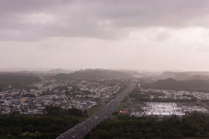 Cars drive along a highway as a cloud of dust from the Sahara Desert blankets most of the Caribbean Sea.