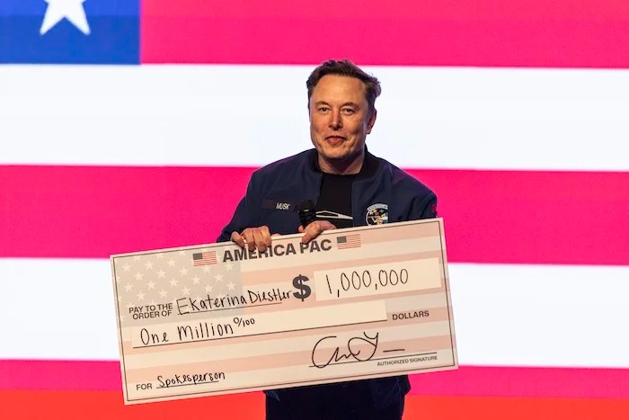 Elon Musk holds up a check during a town hall Sunday, March 30, 2025, in Green Bay, Wisconsin.