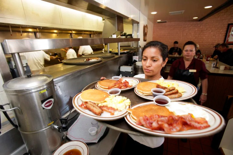Server Sara Perez, of Mesa, Ariz., left, hauls a tray of Grand Slam breakfasts as service assistant Blanca DePaz, of Tempe, Ariz., looks on as hundreds of patrons take advantage of the Denny's free Grand Slam Breakfast national giveaway at a local Denny's restaurant Tuesday, Feb. 9, 2010, in Tempe, Ariz. (AP Photo/Ross D. Franklin)