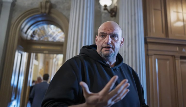 John Fetterman talks to reporters outside the chamber during a vote at the Capitol.
