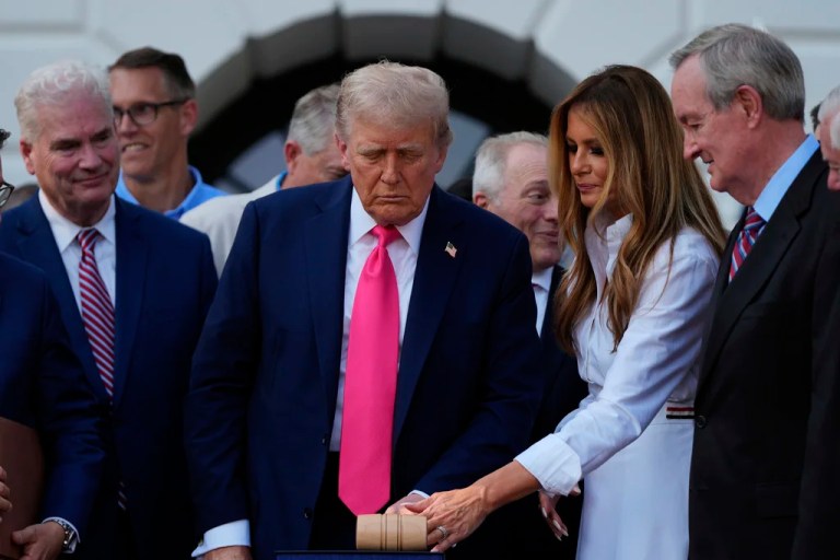 President Donald Trump is joined on stage by first lady Melania Trump after he signed his signature bill of tax breaks and spending cuts at the White House, Friday, July 4, 2025, in Washington, surrounded by members of Congress.