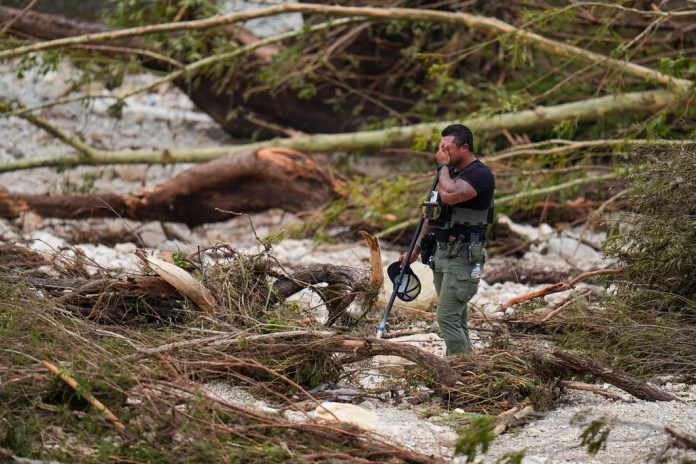 A Sheriff's deputy pauses while combing through the banks of the Guadalupe River near Camp Mystic after a flash flood swept through the area Saturday, July 5, 2025, in Hunt, Texas.