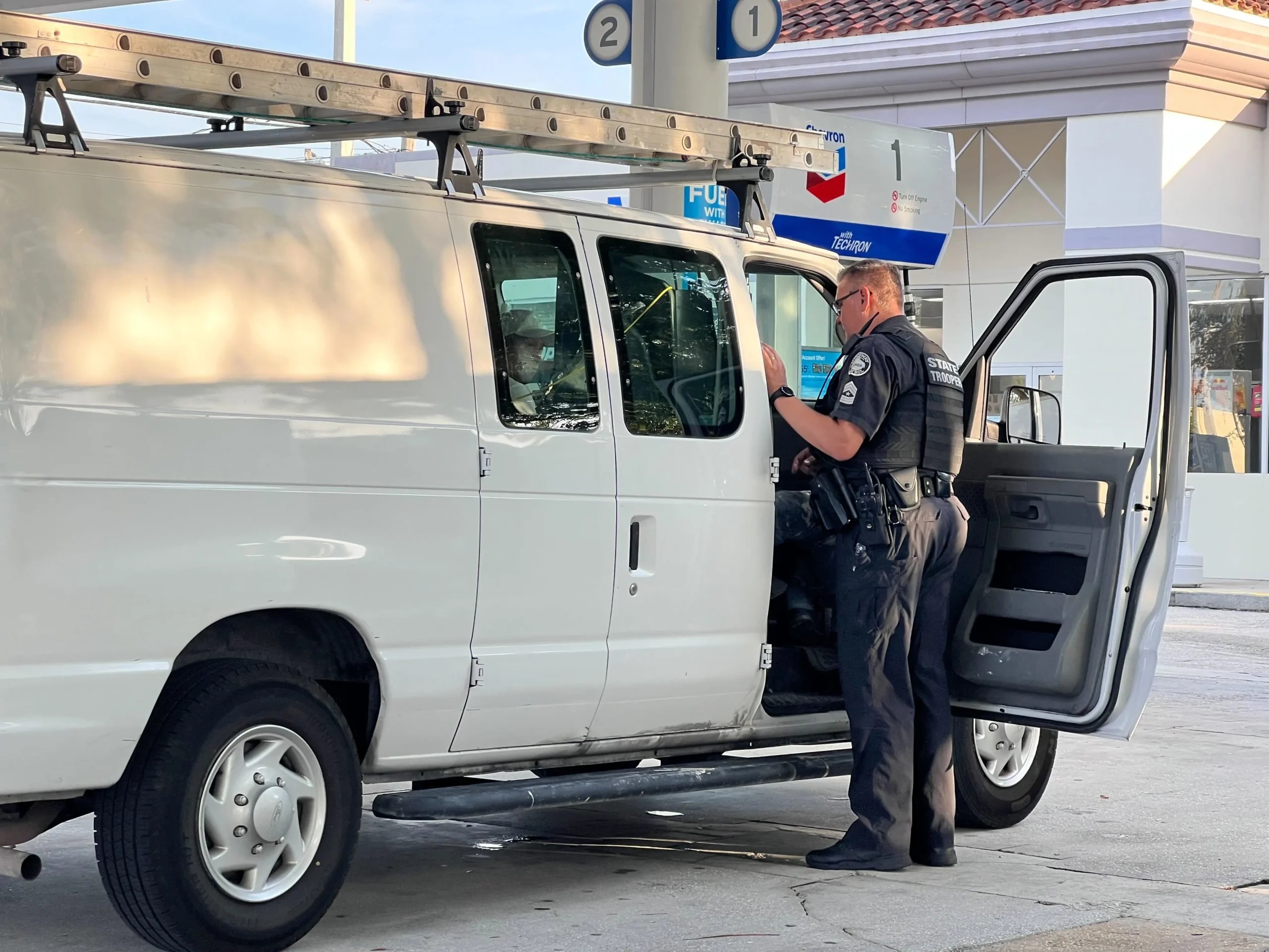 A Florida Highway Patrol state trooper questions a 15-year-old boy about his relation to the driver of the van. (Anna Giaritelli / Washington Examiner)