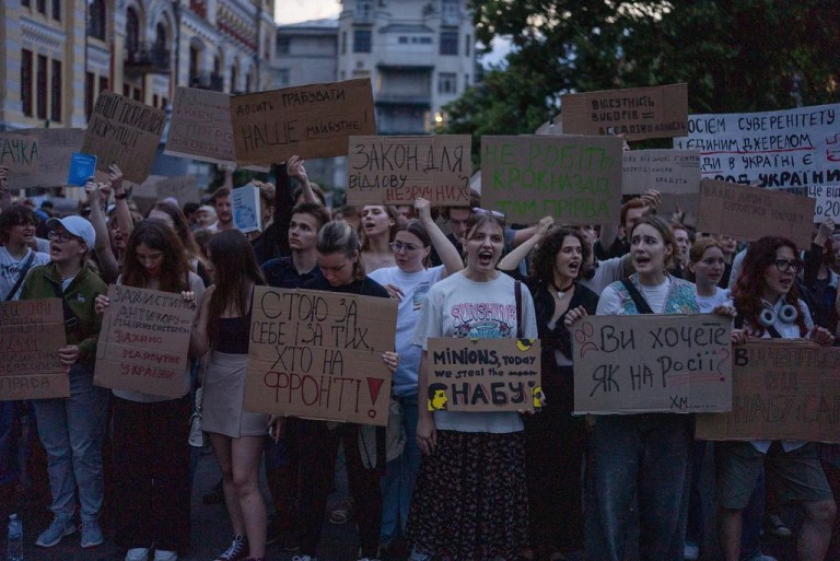 Protesters chant while holding banners that read 