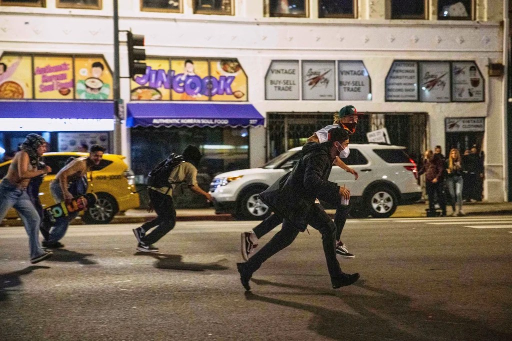 Protesters run to avoid being kettled by police during protests over the Trump administration's immigration raids in Los Angeles, Monday, June 9, 2025.