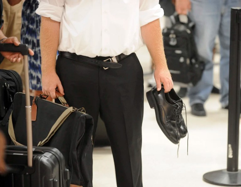 In this Aug. 3, 2011 photo, an experienced airline passenger holds his shoes and has a loosened belt while waiting to go through the Transportation Security Administration security checkpoint at Hartsfield-Jackson Atlanta International Airport.