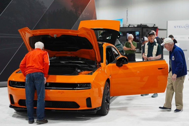 Shoppers look over a 2025 Dodge Charger Daytona hardtop in the Stellantis display at the Colorado Auto Show, April 17, 2025, in Denver.