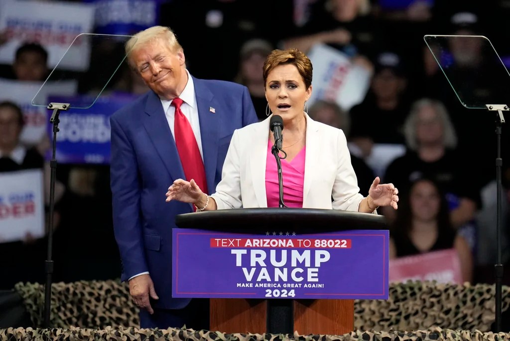 Republican presidential nominee former President Donald Trump listens as Arizona Senate candidate Kari Lake speaks at a campaign rally at the Findlay Toyota Arena Sunday, Oct. 13, 2024, in Prescott Valley, Ariz. 