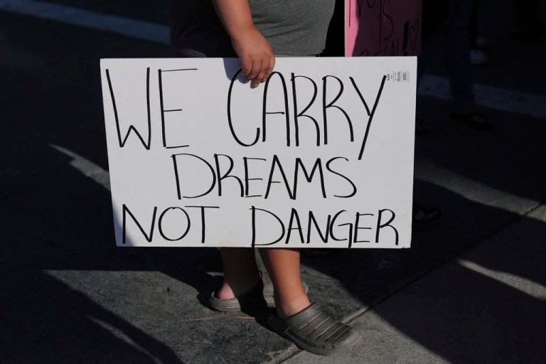 A person carries a sign reading 