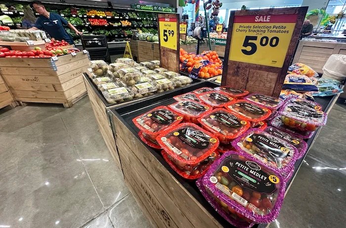 Tomatoes are displayed as a customer shops at a grocery store in Glenview, Ill., Tuesday, July 15, 2025.