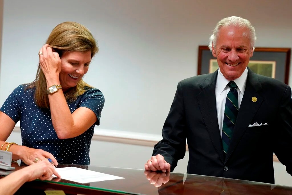 Gov. Henry McMaster, right, smiles as Lt. Gov. Pamela Evette, left, signs her paperwork to run again on a ticket with the governor on Wednesday, July 27, 2022, in Columbia, S.C. McMaster and Evette are the first candidates to file for reelection on a ticket in South Carolina, which previously elected its two top officeholders separately.