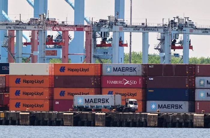 A truck drives by shipping containers at the port of the port of New York & New Jersey in Elizabeth, N.J., Monday May 12, 2025
