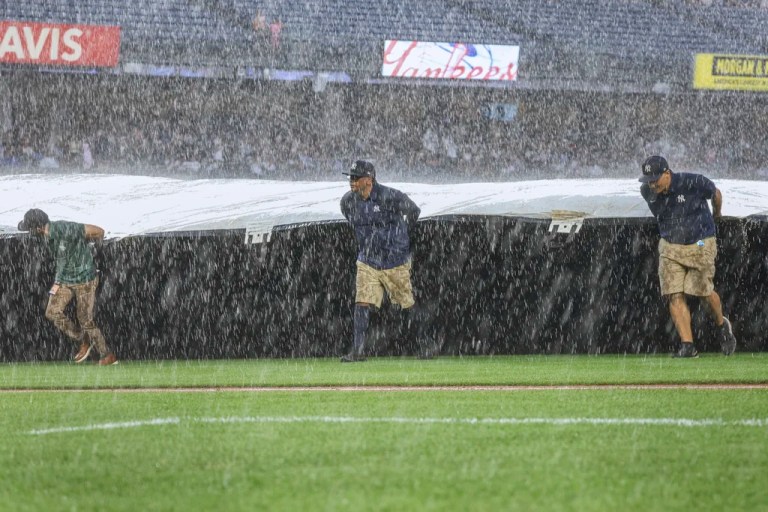 The Grounds crew roll out the tarp during a rain delay in the fifth inning of a baseball game between the New York Yankees and the Tampa Bay Rays, Thursday, July 31, 2025, in New York.