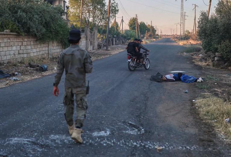 Syrian government forces pass next of a dead fighter from Druze militias, at Mazraa village on the outskirts of the city of Sweida, where clashes erupted between Sunni Bedouin clans and Druze militias, southern Syria, Monday, July 14, 2025.