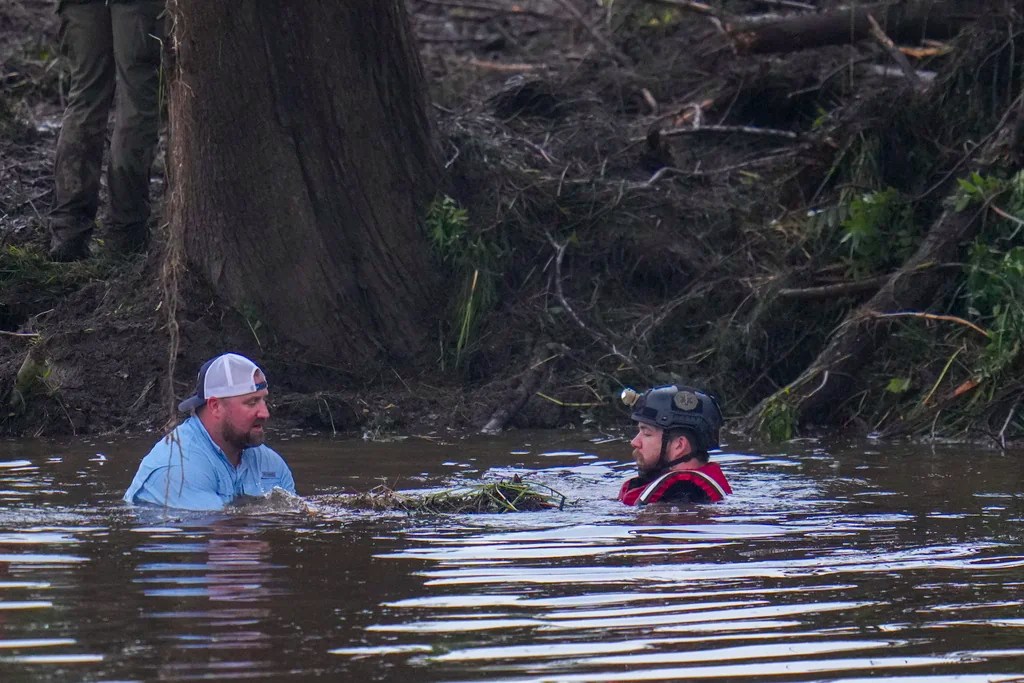 Officials are seen in the Guadalupe River as they assist in recovery efforts after a flash flood swept through the area Sunday, July 6, 2025, in Hunt, Texas.