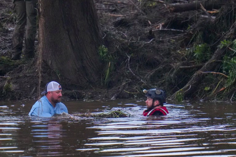 Officials are seen in the Guadalupe River as they assist in recovery efforts after a flash flood swept through the area Sunday, July 6, 2025, in Hunt, Texas.