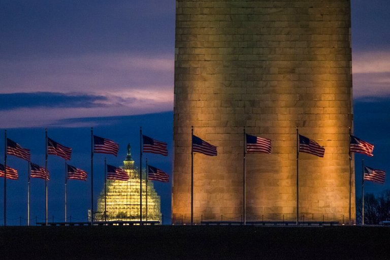 In this Dec. 31, 2015, file photo, flags around the Washington Monument fly in the gentle breeze at daybreak on a warmer than average day in Washington, D.C. The Capitol is in the background.