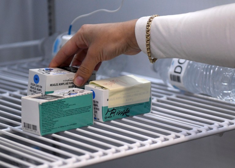 Anna Hicks places the measles, mumps and rubella vaccine in a refrigerator