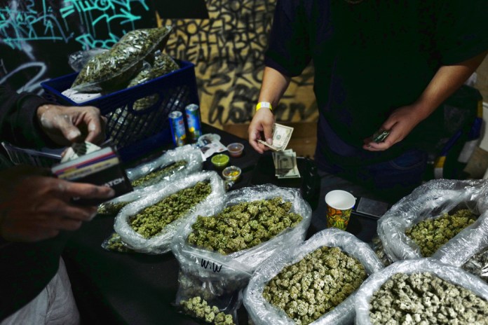 A vendor makes change for a marijuana customer at a cannabis marketplace on April 15, 2019, in Los Angeles.