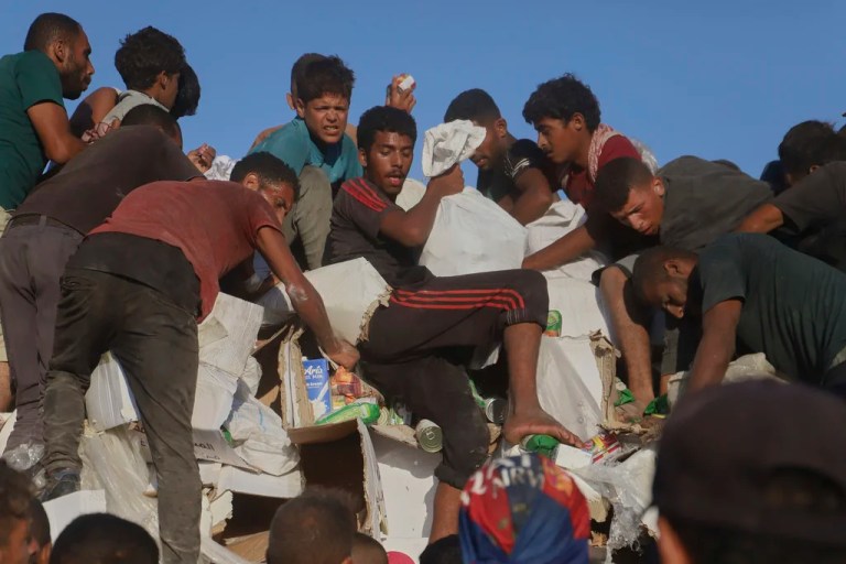 Palestinians struggle to get food and humanitarian aid from the back of a truck as it moves along the Morag corridor near Rafah, in the southern Gaza Strip, Monday, Aug. 4, 2025.