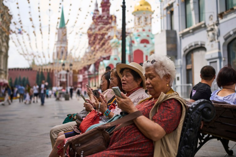 People look at their phones near the Kremlin in Moscow, July 16, 2025.