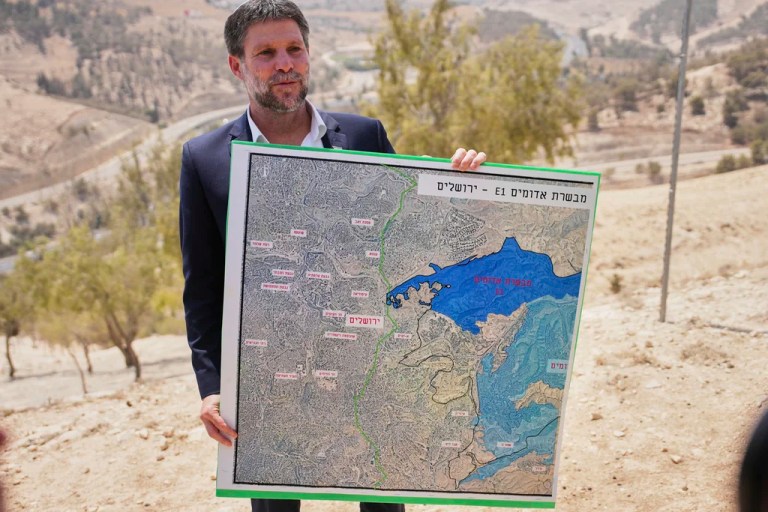 Israeli Finance Minister Bezalel Smotrich holds a map that shows the E1 settlement project during a press conference near the settlement of Maale Adumim, in the Israeli-occupied West Bank, Thursday, Aug. 14, 2025. (AP Photo/Ohad Zwigenberg)