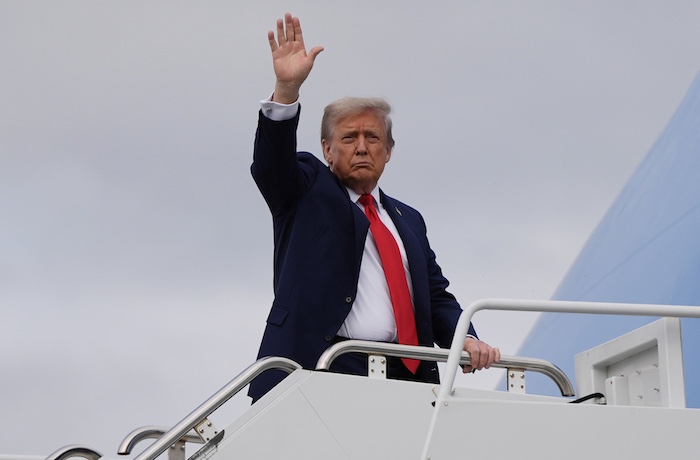 President Donald Trump waves as he boards Air Force One after meeting with Russia's President Vladimir Putin