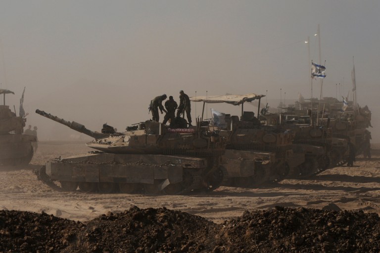 Israeli soldiers stand on top of a tank parked in an area near the Israeli-Gaza border, as seen from southern Israel, Monday, Aug. 18, 2025.