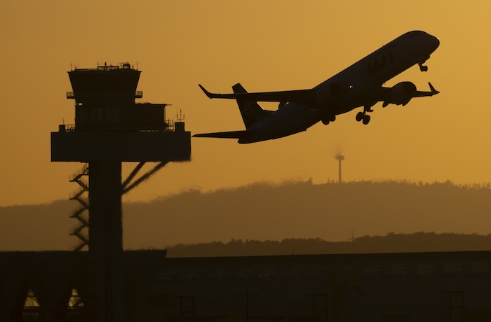 A passenger plane takes off from Frankfurt Airport in the last light of the day, flying past the tower of German Air Traffic Control (DFS), in Frankfurt/Main, Germany, Monday, Aug. 18, 2025.