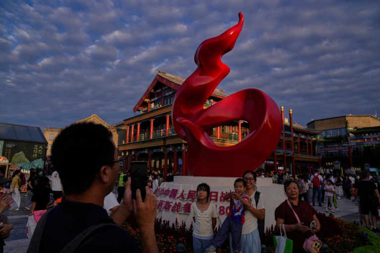 A man takes a photograph of their family members in front of a sculpture displayed ahead of the Sept. 3 victory Day military parade in Beijing, China, Sunday, Aug. 24, 2025.