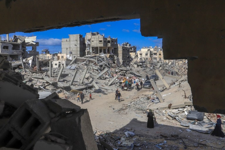 FILE - Palestinians walk through the rubble caused by the Israeli air and ground offensive in Rafah, southern Gaza Strip, Monday, Jan. 20, 2025. (AP Photo/Mariam Dagga, File)