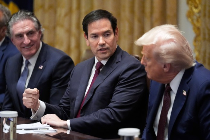President Donald Trump, right, listens as Secretary of State Marco Rubio speaks during a Cabinet meeting in the White House, Tuesday, Aug. 26, 2025, in Washington. Interior Secretary Doug Burgum looks on.