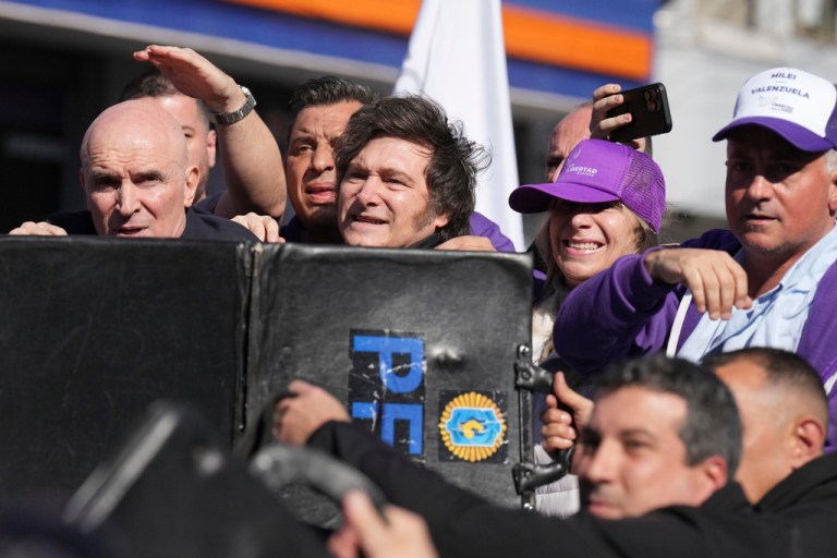 Police shield Argentine President Javier Milei and his sister, Secretary General of the Presidency, Karina Milei, from objects thrown at them by protesters amid a campaign rally ahead of legislative provincial elections in Lomas de Zamora, Argentina, Wednesday, Aug. 27, 2025.