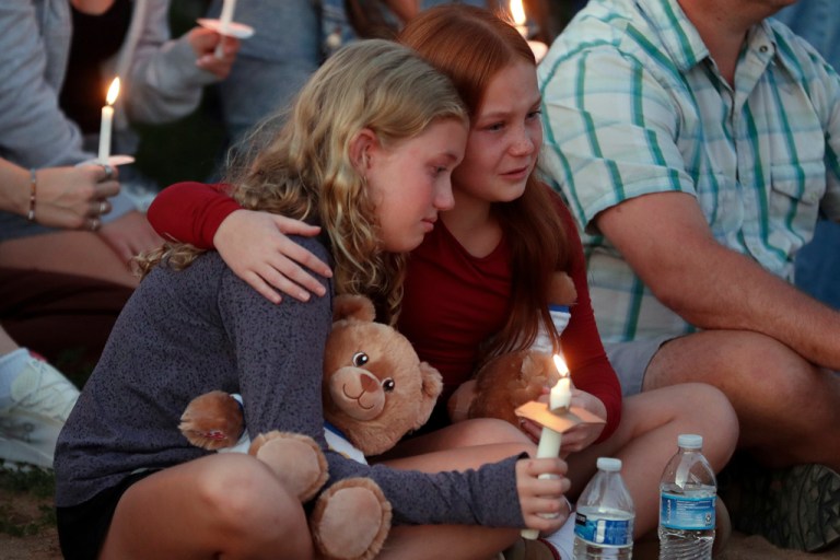 People gather at a vigil at Lynnhurst Park after a shooting at the Annunciation Catholic School.