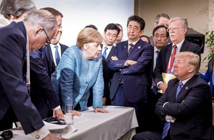 German Chancellor Angela Merkel (center) speaks with President Donald Trump (seated right) during the G7 Leaders Summit in La Malbaie, Quebec, Canada on June 9, 2018. (Jesco Denzel/German Federal Government via AP)