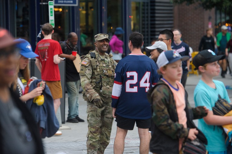 People talk with a member of the D.C. National Guard as they patrol the area outside Nationals Park in Washington, Tuesday, Aug. 19, 2025.