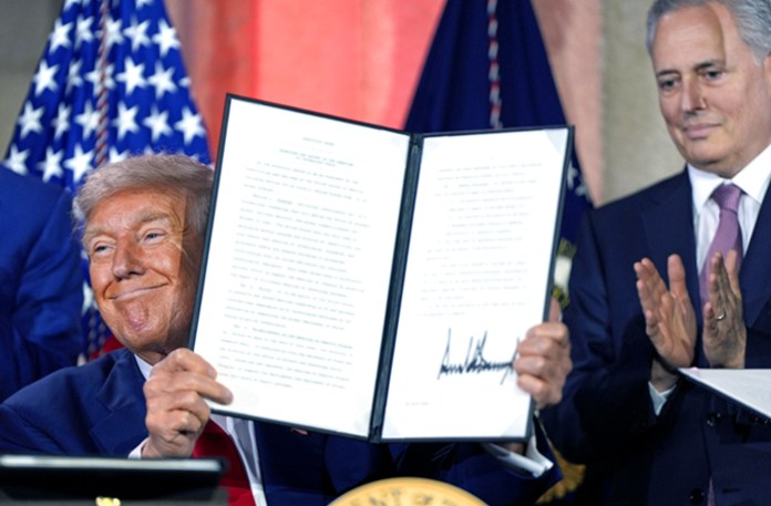As White House AI adviser David Sacks, right, looks on, President Donald Trump holds a signed executive order at an AI summit in Washington. D.C., July 23, 2025. (Julia Demaree Nikhinson/AP)