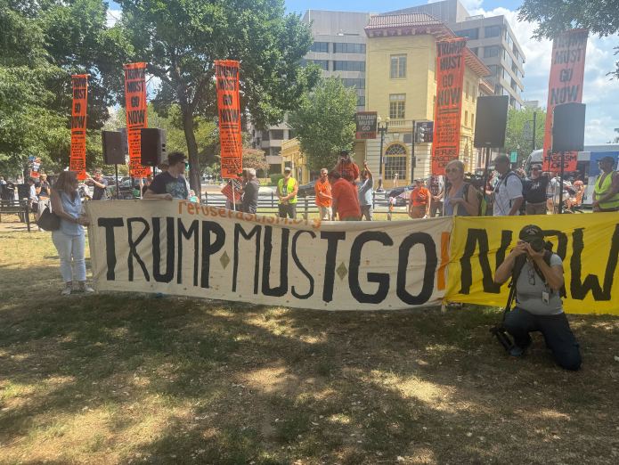 Protesters hold banners saying "Trump must go now" in Washington, D.C., on Saturday, Aug. 16, 2025. (Washington Examiner)